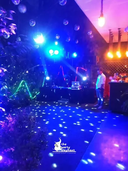 The DJ and dance floor area for the neon party, with spotlights, hanging disco balls, and neon light tubes creating an energetic and immersive space for dancing.