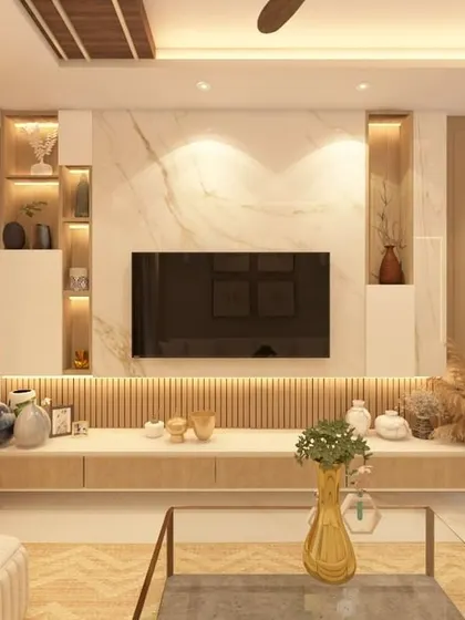 This television unit is set against a marble-clad wall, flanked by built-in display niches with warm backlighting. The combination of fluted wood paneling below and clean white cabinetry creates a media center that is both a storage solution and a decorative focal point.