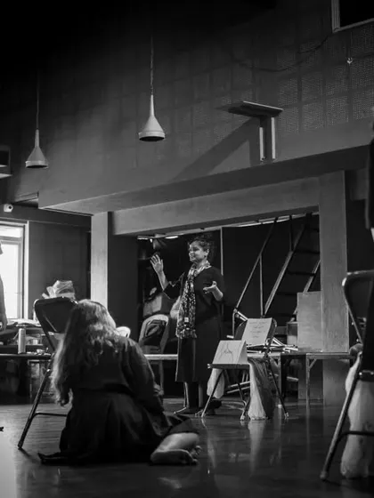 A black and white photo from a workshop, capturing the mood and focus of the artists. The different levels of the space, including the mezzanine, add depth to the frame.