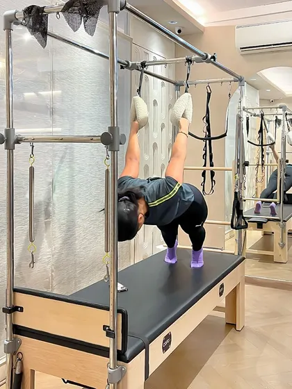 Contemporary Pilates, like this hanging exercise on the Cadillac, blends classic principles with modern exercise science for a dynamic workout.