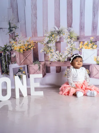 A portrait of the proud big sister, sitting patiently by the "ONE" sign. Including siblings in the photoshoot is a wonderful way to celebrate the whole family.