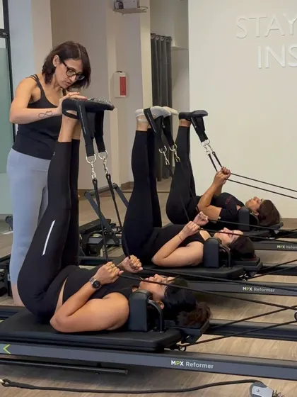 An instructor gives a hands-on correction to a group of women during a feet-in-straps series, ensuring everyone is moving safely and effectively.