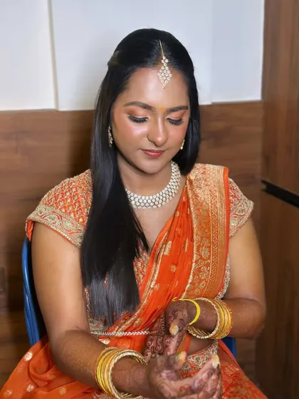 A beautiful blend of soft glam and tradition. I chose warm, peachy tones for the eyes and cheeks to complement her orange silk lehenga, creating a look that is both fresh and timeless.