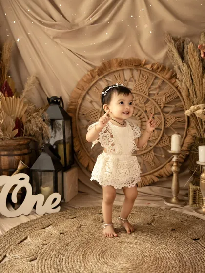 A happy dance from the birthday girl in her boho-chic lace outfit. This theme is perfect for creating timeless and artistic milestone photos.