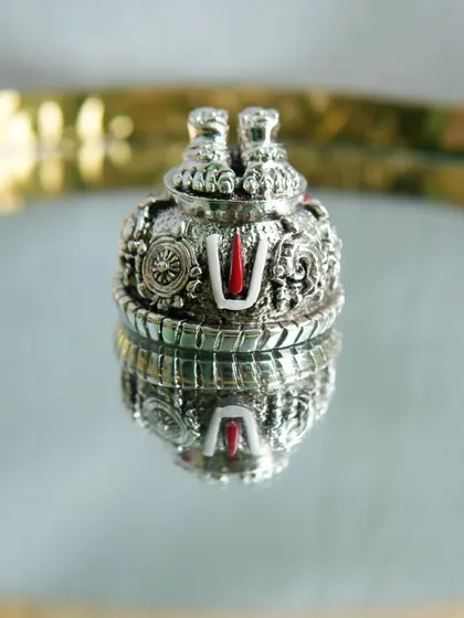 A detailed silver souvenir featuring the Tirupati Nammam and Sanku. This premium gift comes in a beautiful box, perfect for housewarmings or other auspicious events.