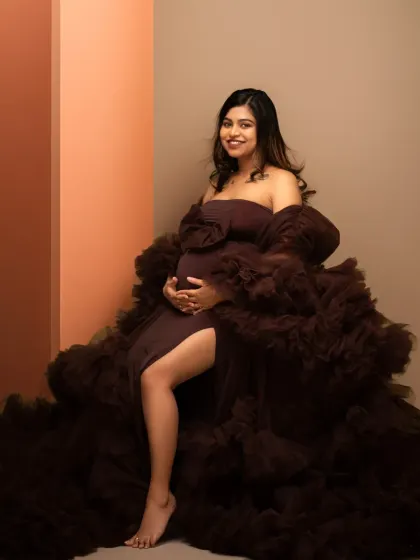 A modern and stylish maternity portrait. The rich brown gown and color-blocked background create a contemporary yet timeless look for this expecting mother.