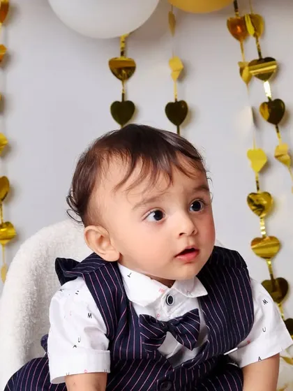 A sweet close-up of the birthday boy, capturing his curious expression against the backdrop of shimmering gold heart decorations.