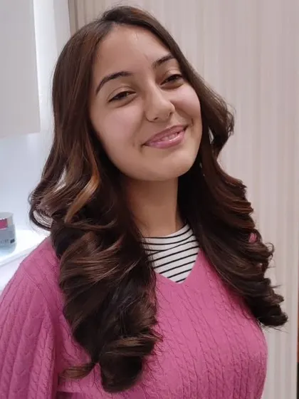 A closer look at this beautiful hair color and style. The soft curls perfectly complement the subtle highlights, creating a look that is both elegant and modern.
