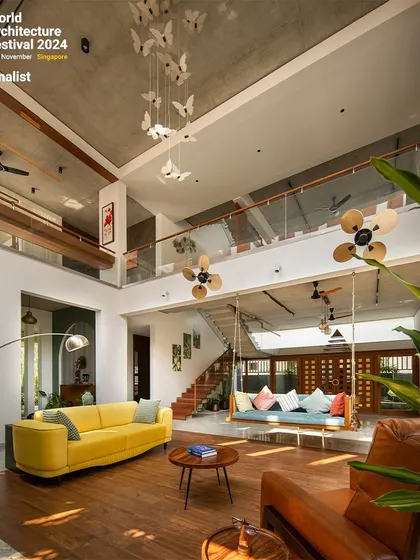 This view emphasizes the verticality of the space and the connection to the upper floor. The careful placement of furniture defines different functional zones within the open-plan layout.