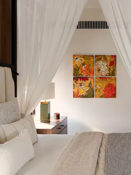 A detail of the art and bedside lighting in the master bedroom. The warm colors in the floral artwork add a soft, personal touch to the neutral space.