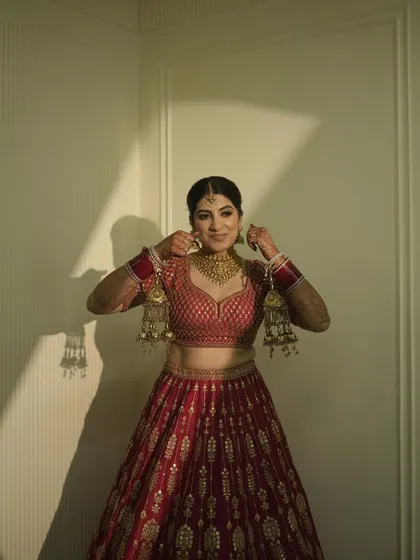 A candid moment of my sister getting ready. Her classic gold jewelry and red lehenga are quintessential bridal elements, and her makeup was designed to match that elegance.