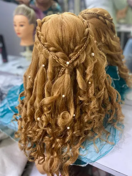 A full view of the braided crown and curly hairstyle created by a student. This showcases their skill in both braiding and styling.