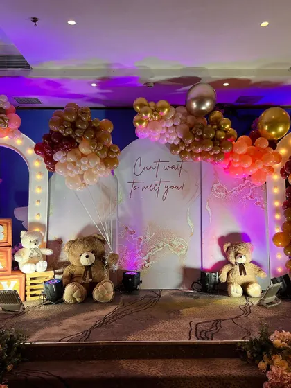 A "Can't wait to meet you!" baby shower stage with multiple teddy bears and balloon clouds in warm, neutral tones.