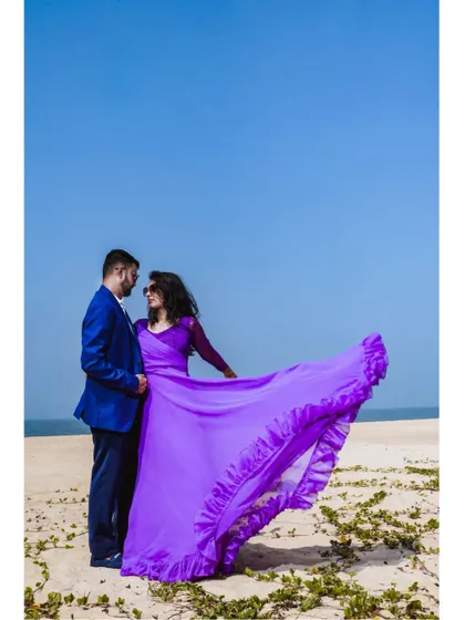 The flowing fabric of the lavender tail gown creates beautiful shapes in the wind, perfect for a dynamic and romantic beach photoshoot.
