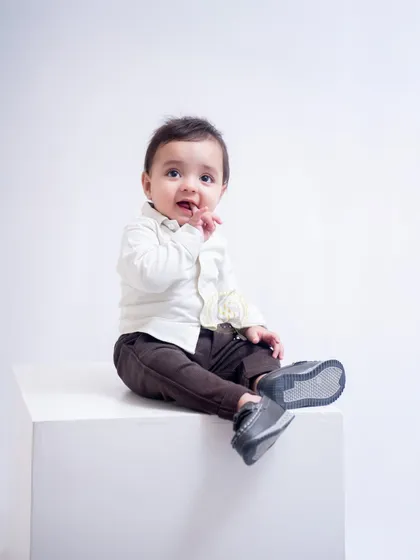 A thoughtful moment captured during a baby photoshoot. The minimalist white setting ensures that the baby's sweet expression and tiny features are the main focus.