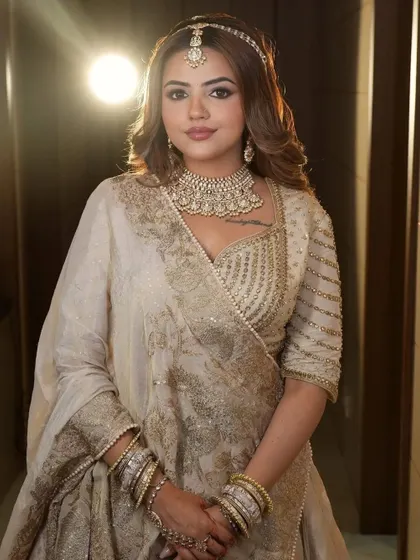 A confident pose in the ivory and gold lehenga, highlighting the detailed beadwork on the blouse and the heavy choker necklace.