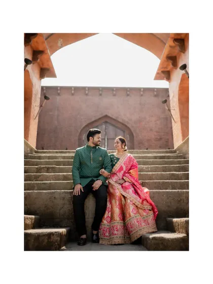 The couple sits on the steps of a historic structure, sharing a look. This pre-wedding photo combines grand architecture with an intimate moment.
