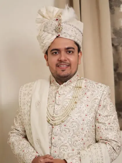 A three-quarter shot of the groom in his wedding attire. The overall look is cohesive, from the well-styled hair to the elegant sherwani.