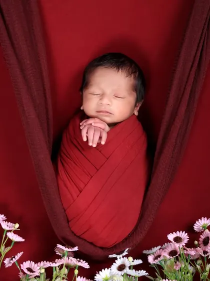 A creative newborn pose using a hanging sling prop. We ensure the baby is always safe and secure while we capture these unique and beautiful images.