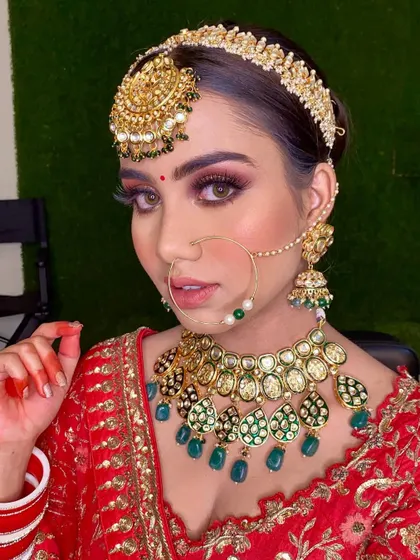 A close-up of this stunning bridal look. The combination of a red lehenga, green kundan jewelry, and dramatic eye makeup is pure perfection.