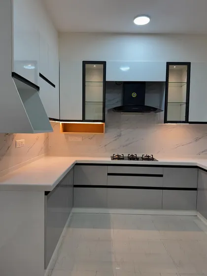 This modern kitchen features a sophisticated two-tone design with glossy white upper cabinets and sleek grey lower cabinets. The black accents on the handles and chimney create a sharp, contemporary look.