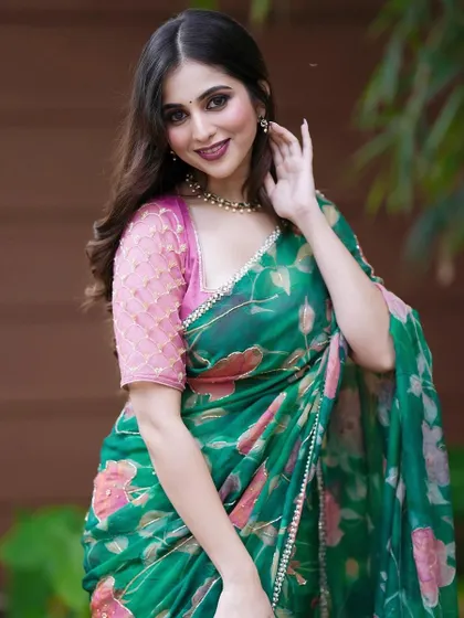 A close-up of Niveditha Gowda in the green floral saree, showing the delicate embroidery on the pink blouse.
