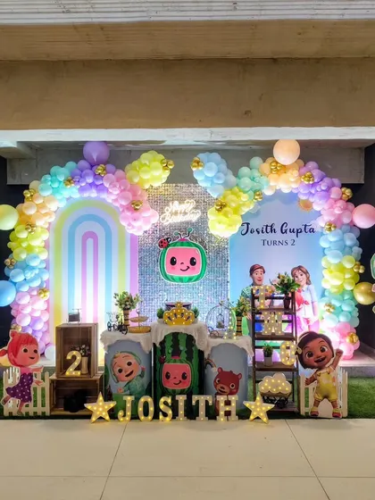 A pastel-colored Cocomelon theme for a second birthday. This decor features a sequin backdrop, rainbow arches, and marquee letter's spelling out the birthday boy's name.