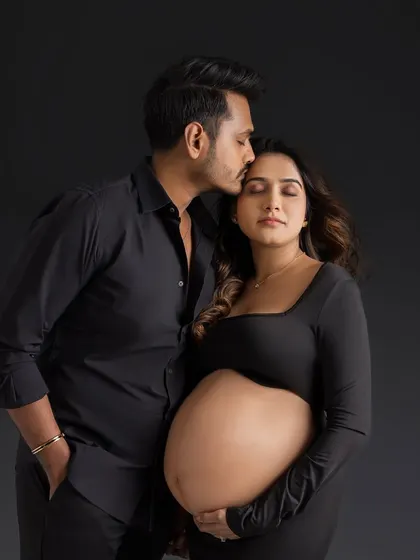 A tender kiss on the forehead is a timeless symbol of love and protection. This classic pose beautifully captures the father-to-be's affection for his partner and their growing family.