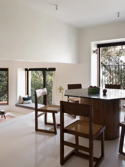 A hexagonal dining table I designed to create a unique focal point in this multi-level space. The solid, sculptural base is made of wood, while the top is a polished, dark stone, offering a durable and elegant surface.