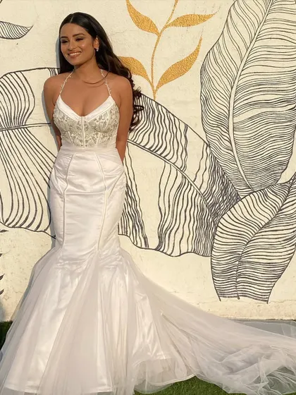 The bride looks radiant and happy, her hair styled in simple, elegant waves that complement her mermaid-style gown.