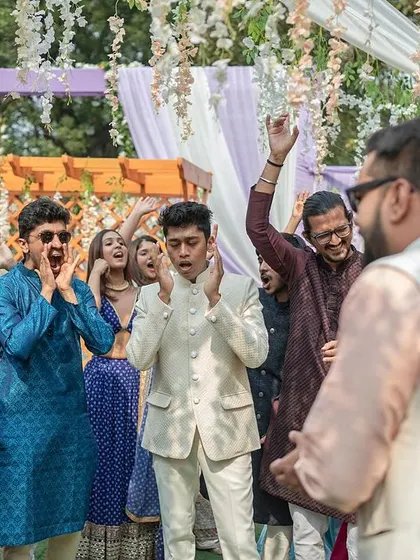 The groom's friends cheering him on as he arrives at the wedding venue.