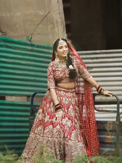 Another shot of this beautiful morning bride in her red lehenga. The outdoor lighting highlights the soft, glowing finish of the makeup, ensuring she looks perfect in every candid moment.