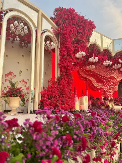 A view of the stage from the side, where mirrored arches are framed by a profusion of red and purple flowers, creating a scene of opulent drama.