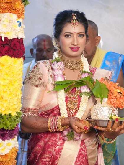 This bride is ready for her ceremony, showcasing a beautiful look with a bright pink lip that pops against her elegant saree. The makeup is designed to be long-lasting and picture-perfect.