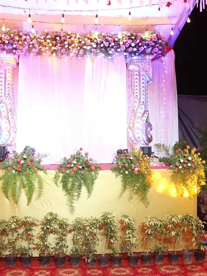 A beautifully decorated stage setup with ornate pillars, a lush floral cornice, and soft, elegant drapery, ready for the main ceremony.