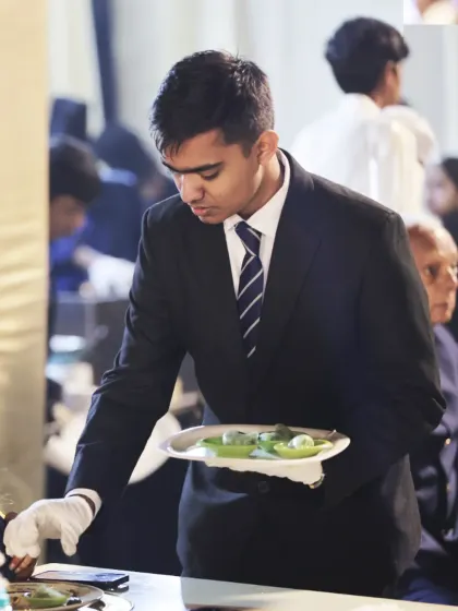 A server attends to a guest's needs with professionalism and care. Our team is trained to be attentive, courteous, and efficient, ensuring a smooth and enjoyable dining experience for everyone.