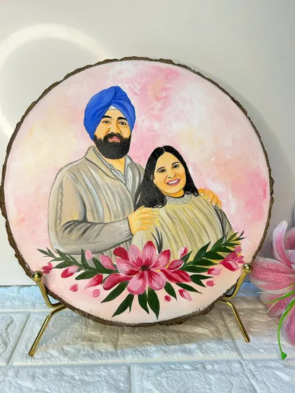A close-up of a finished couple portrait on a wood slice, displayed on a classy golden stand. The soft pink tones and floral details make it a beautiful decorative piece.