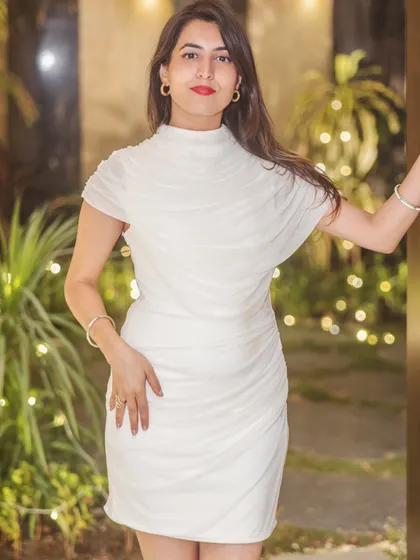 I'm standing by the doorway in white, with greenery and warm lights behind me in the private-party artist portrait series.