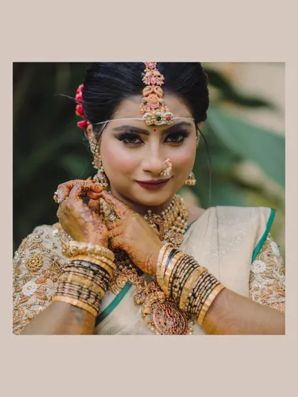 A close-up of the bride adjusting her bangles, a classic pose that highlights her intricate henna and traditional jewelry.