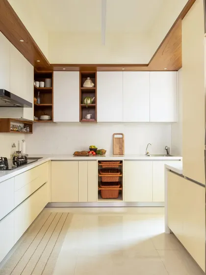 A bright and airy kitchen with off-white cabinetry, a wooden ceiling detail, and open wicker basket storage for a warm, organic feel.