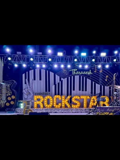 A panoramic view of the epic Rockstar stage at night, complete with a drum kit, giant guitar prop, and professional lighting rig.