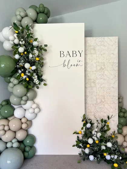 A "Baby in Bloom" theme with a refreshing green and white color palette. The design incorporates a balloon garland with pops of lemon and delicate flowers for a natural, organic feel.