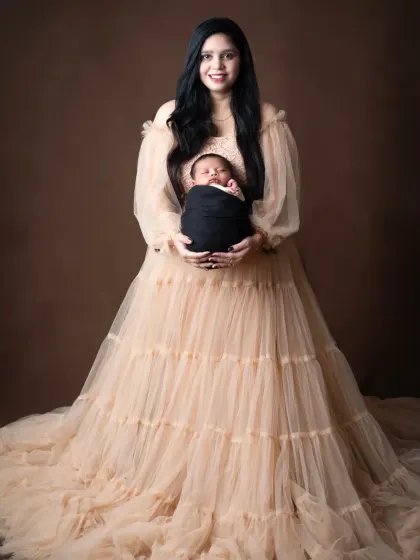 A classic mother and child portrait, with the mom holding her newborn against a simple, elegant backdrop.