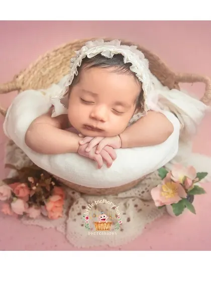 A classic basket pose with a vintage feel. The lace bonnet and soft floral accents add a timeless and delicate touch to this newborn portrait.
