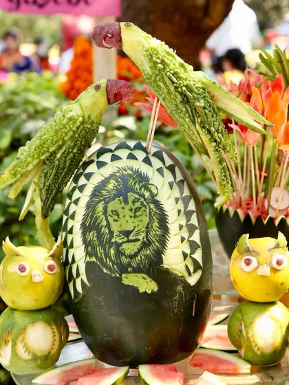 A magnificent display of fruit and vegetable art, including a lion carved into a watermelon and parrots made from bitter gourds. This is edible art at its finest.