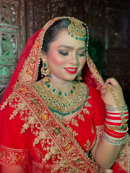 A classic red bridal look is always a winner. Here, I've paired a vibrant red lip with gold and green jewelry, creating a timeless and royal appearance for her special day.
