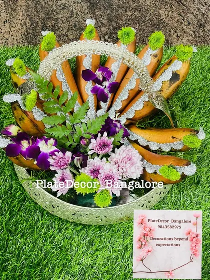 This fruit basket features bananas decorated with delicate white lace and purple orchids, creating a sophisticated and unique look.