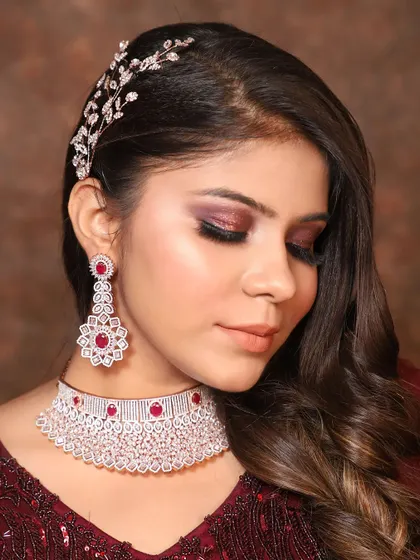 Make a statement at your next party with this gorgeous American Diamond choker set. The intricate design is studded with high-quality AD stones and beautiful ruby-colored accents, paired with matching drop earrings for a complete, polished look.