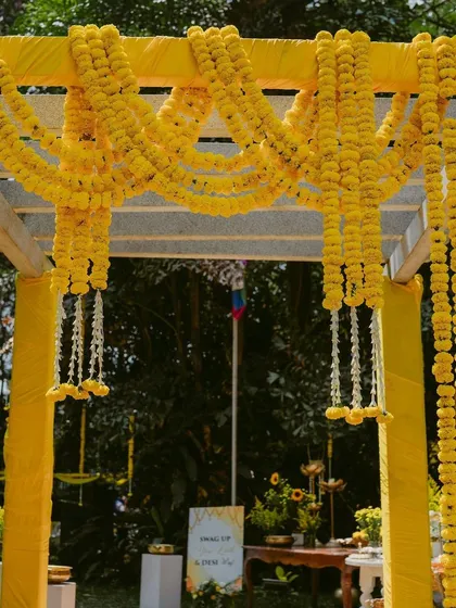 A grand entrance for a Haldi ceremony, with a canopy of marigold garlands creating a vibrant yellow passage.