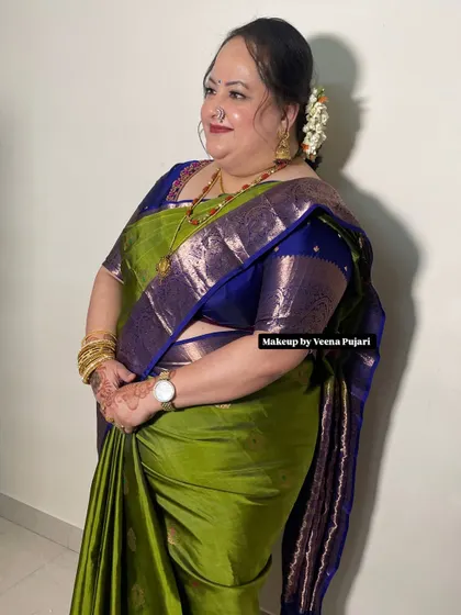 A side profile of this elegant lady, ready for a family function. Her green and blue silk saree is complemented by a simple, graceful hairstyle.